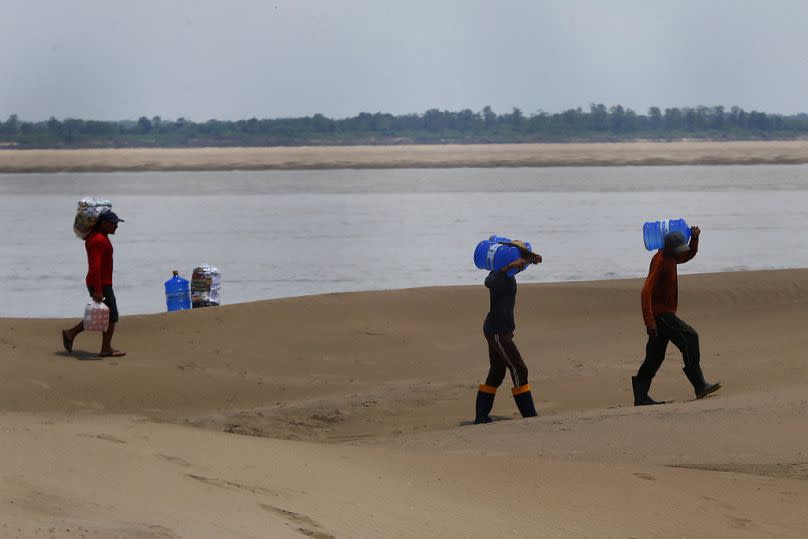 Habitantes de una comunidad del estado de Amazonas transportan alimentos y recipientes con agua potable, distribuidos debido a la sequía y las altas temperaturas.