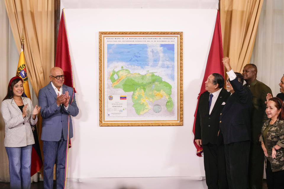National Assembly President Jorge Rodriguez, left, and Chairman of the Special Commission for the Defense of Guyana Essequibo Hermann Escarra, along with fellow legislators, applaud after unveiling Venezuela's new map that includes the Essequibo territory, a swath of land that is administered and controlled by Guyana but claimed by Venezuela, in Caracas, Venezuela, Friday, Dec. 8, 2023. (AP Photo/Matias Delacroix)