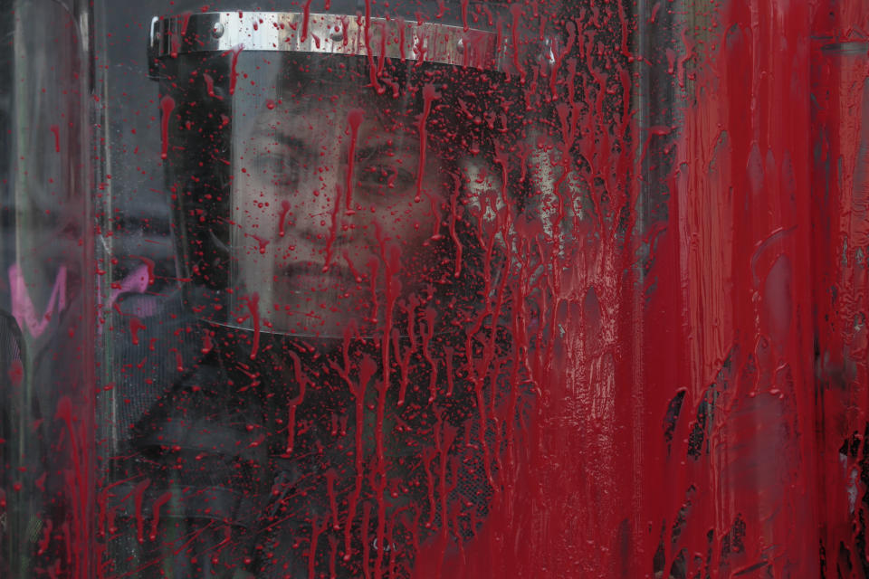 A police officer stands behind her riot shield covered in red paint during an International Women's Day march in Mexico City's main square, the Zocalo, Sunday, March 8, 2020. Protests against gender violence in Mexico have intensified in recent years amid an increase in killings of women and girls.(AP Photo/Rebecca Blackwell)
