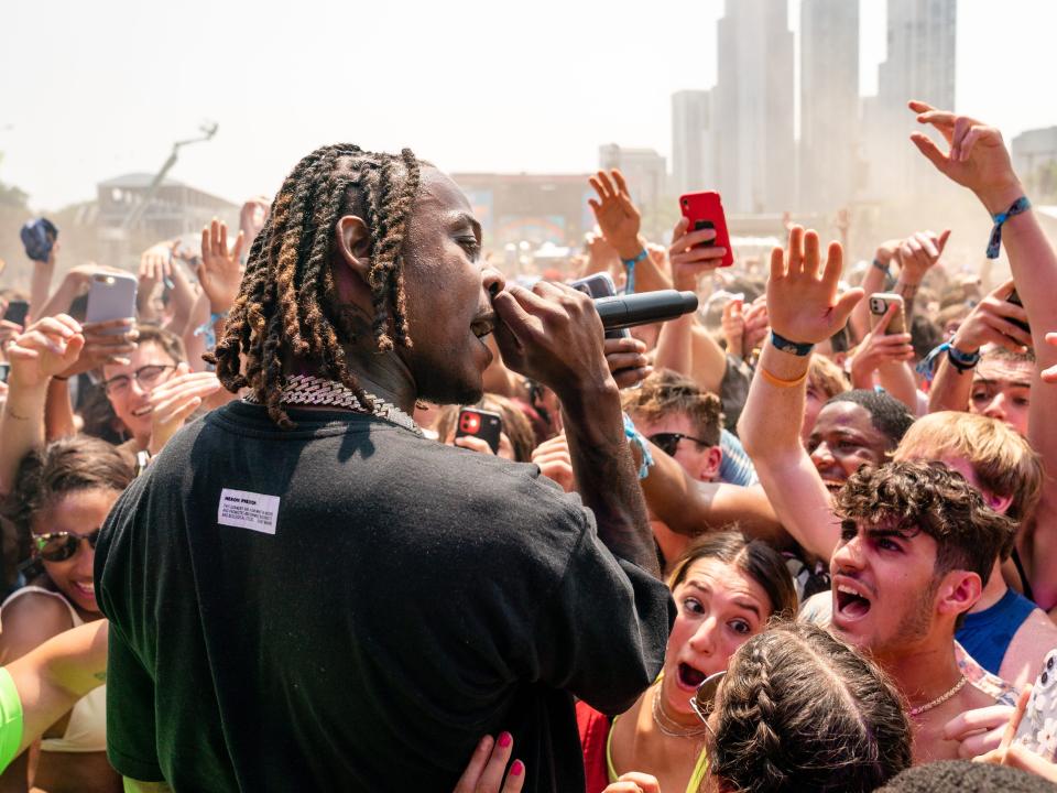 Flipp Dinero faces a crowd of people with a microphone in his hand.