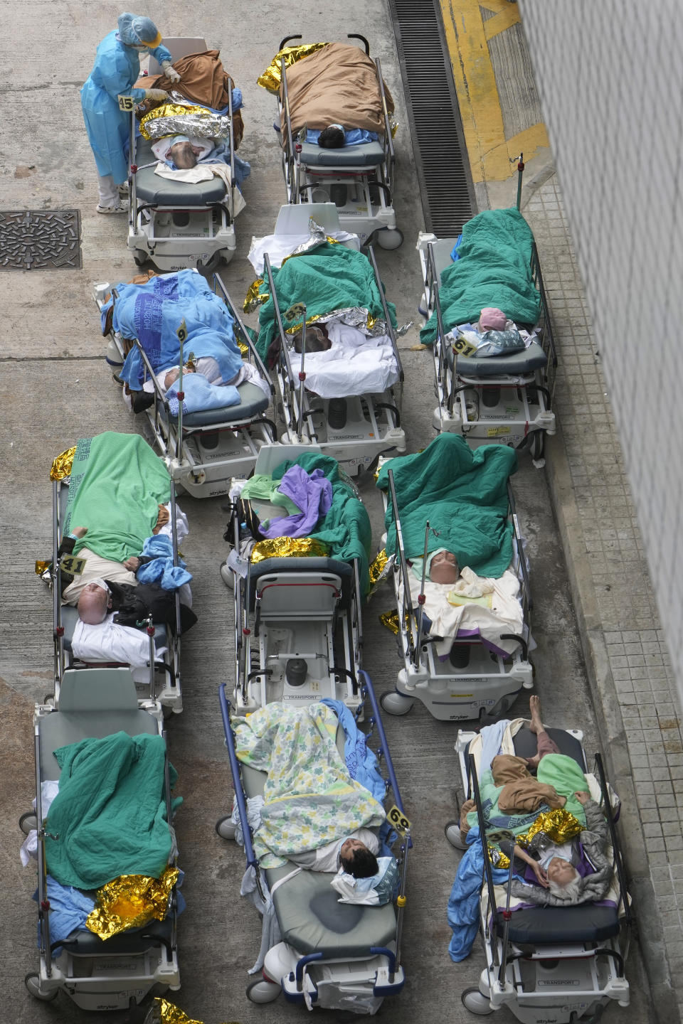 Patients lie on hospital beds as they wait at a temporary holding area outside Caritas Medical Centre in Hong Kong Wednesday, Feb.16, 2022. There was visible evidence that Hong Kong hospitals were becoming overwhelmed by the latest COVID surge, with patients on stretchers and in tents being seen to by medical personnel on Wednesday outside the Caritas hospital. (AP Photo Vincent Yu)