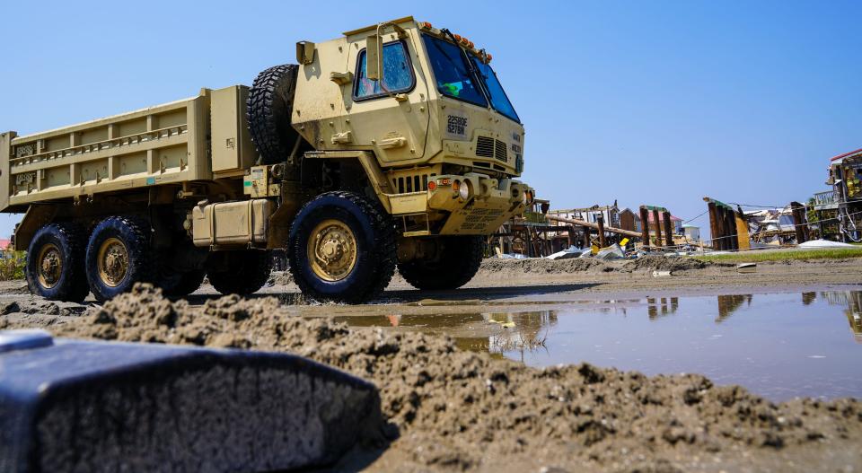 A National Guard dump truck clears sand from the inundated streets of Grand Isle, Louisiana following the passage of Hurricane Ida.