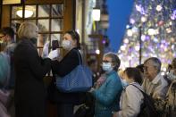 A theater controller measures spectators' temperature at an entrance of Chekhov'v theater in the center of Moscow, Russia, Friday, Sept. 25, 2020. Moscow authorities have issued a recommendation for the elderly to stay at home and for employers to allow as many people as possible to work remotely, following a rapid growth of the coronavirus caseload in the Russian capital. (AP Photo/Alexander Zemlianichenko)