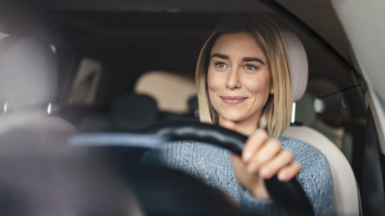 portrait of smiling young woman driving a car