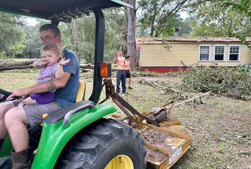 John Slone II gives his granddaughter, Kinley, 2, a ride as he drags debris from his house on Aug. 31, 2023, a day after Hurricane Idalia knocked a large oak tree onto it in the small community of McAlpin in Suwannee County.