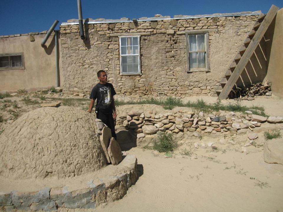 This Oct. 1, 2012 photo shows tour guide Robert Francis gesturing toward an outdoor oven outside an adobe dwelling on a tour of the Acoma Pueblo at the Sky City Cultural Center west of Albuquerque in New Mexico. Tours of the pueblo tell the story of the Acoma people, who have lived on a mesa 370 feet above the desert floor for nearly 1,000 years, surviving centuries of challenges from the Spanish conquistadors to modern times. (AP Photo/Beth Harpaz)