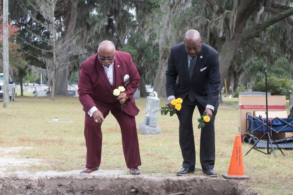 Chatham County Commission Chairman Chester Ellis, left, and Savannah Mayor Van Johnson place flowers into the burial site of 500 unclaimed cremated remains from the Chatham County Coroner's Office on Wednesday. 