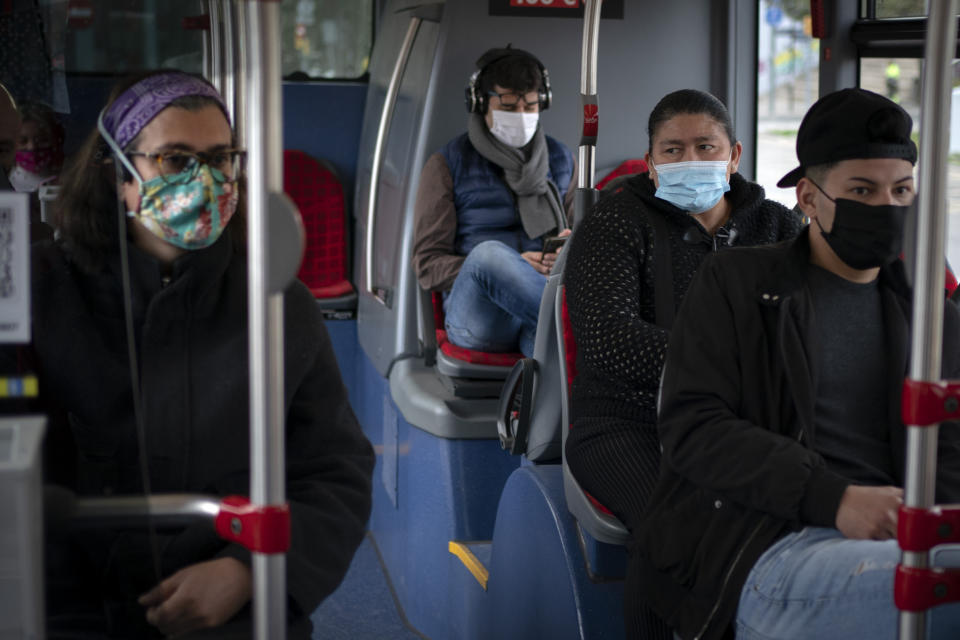 A passenger looks at Victoria Martinez, left, as they travel in a bus in Barcelona, Spain, Monday, Feb. 8, 2021. By May this year, barring any surprises, Martinez will complete a change of both gender and identity at a civil registry in Barcelona, finally closing a patience-wearing chapter that has been stretched during the pandemic. The process, in her own words, has also been “humiliating.” (AP Photo/Emilio Morenatti)