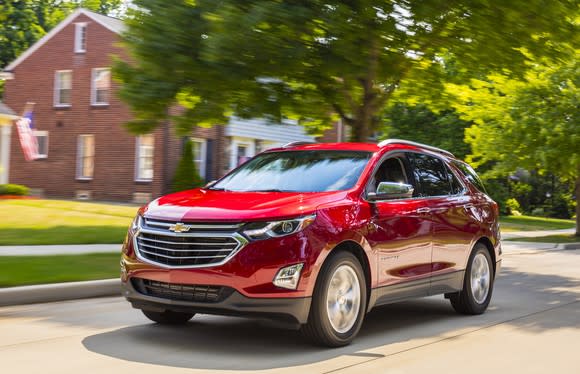 A red 2018 Chevrolet Equinox crossover SUV on a suburban street.