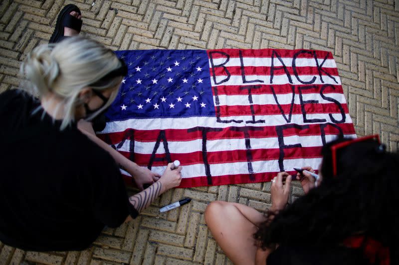 Demonstrators write Black Lives Matter on a U.S. flag during a protest against racial inequality in the aftermath of the death in Minneapolis police custody of George Floyd, at Grand Army Plaza in the Brooklyn borough of New York City