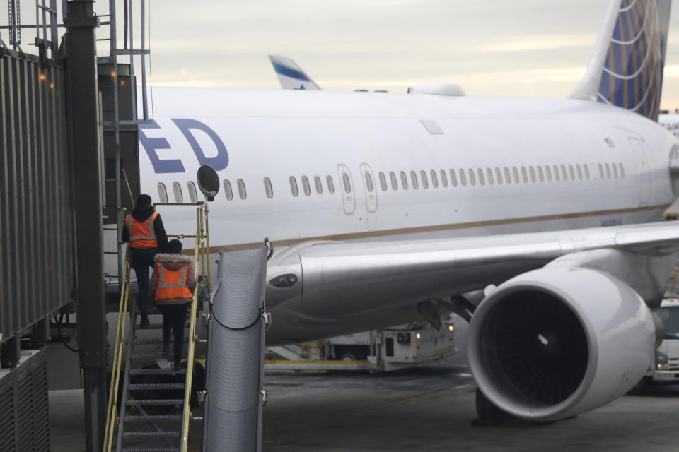 In this Jan. 23, 2019, photo employees walk up a ramp toward a ramp where a United Airlines jet is parked at a gate Newark Liberty International Airport in Newark, N.J. United Airlines reports financial results on Tuesday, July 16. (AP Photo/Julio Cortez)