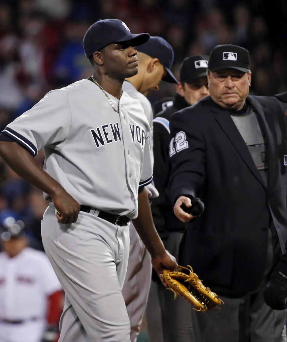 El umpire principal Gerry Davis expulsa a Michael Pineda, el pitcher abridor de los Yanquis de Nueva York, tras detectar una sustancia extraña en su cuello durante el segundo inning del juego ante los Medias Rojas de Boston el miércoles 23 de abril de 2014. (AP Foto/Elise Amendola)