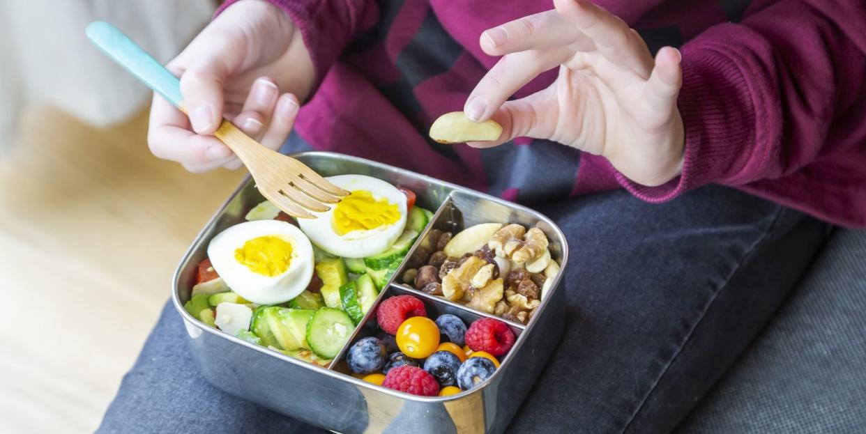 healthy lunch box with trail mix and berries, avocado salad