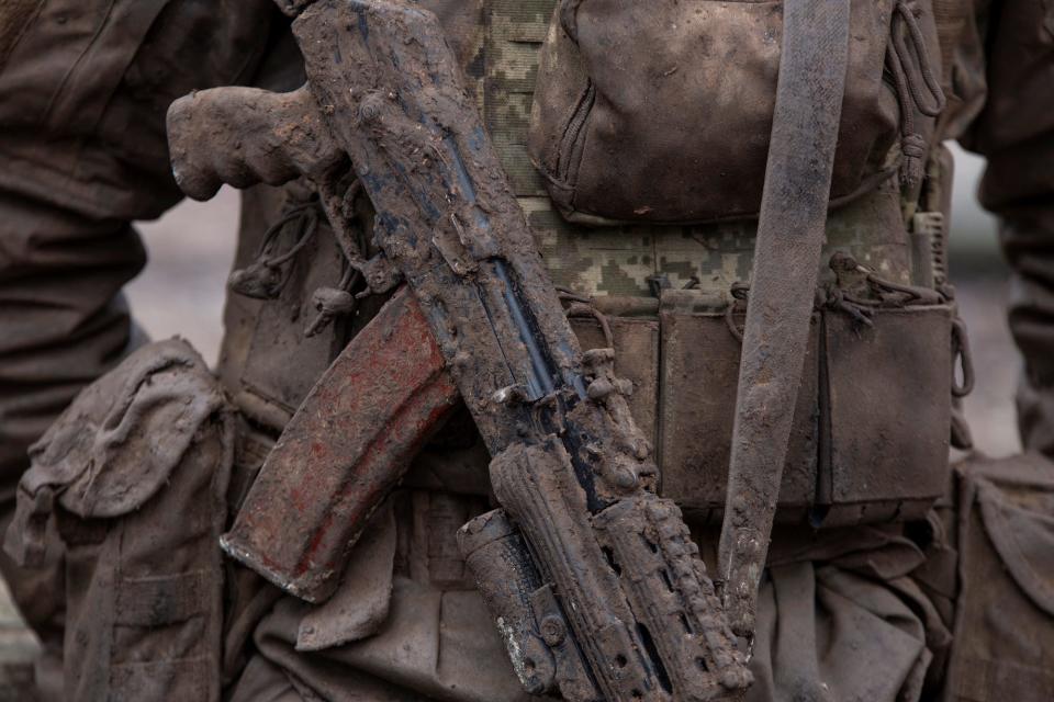 A mud-covered AK-74 around the neck of a Ukrainian solder in camouflage gear