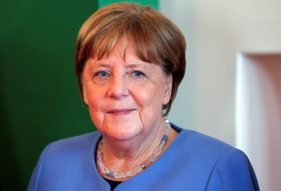 Angela Merkel trägt ein blaues Oberteil und lächelt