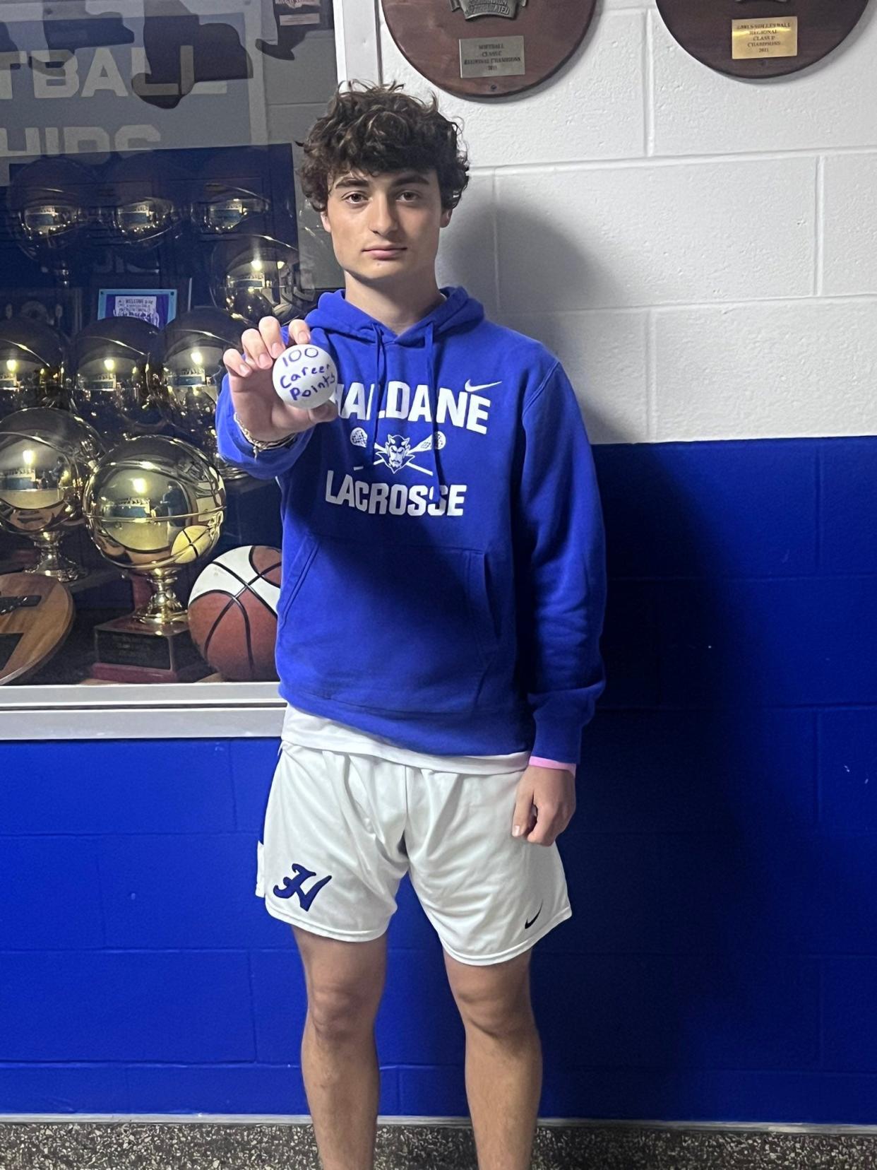 Haldane boys lacrosse player Liam Gaugler poses with the souvenir ball after scoring his 100th career point in the Blue Devils' win on April 22, 2023.