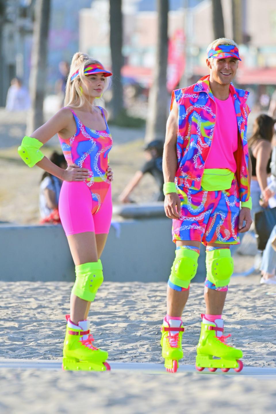 Margot Robbie and Ryan Gosling as Barbie and Ken for the new Barbie film. They wear neon spandex clothing and bright yellow roller skates. (Getty Images)