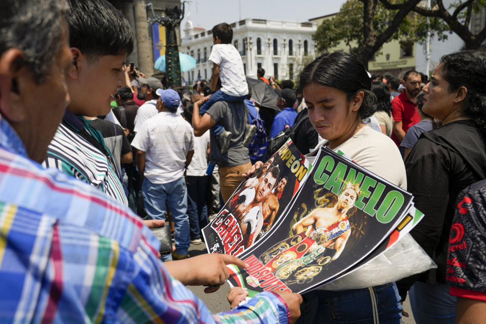 Fans buy posters of Mexican boxer Saul "Canelo" Alvarez during his weigh-in ceremony in Guadalajara, Mexico, Friday, May 5, 2023. Alvarez and John Ryder of Britain will meet for a super middleweight championship fight at Akron Stadium on May 6. (AP Photo/Moises Castillo)