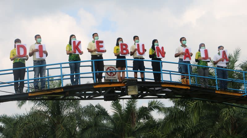 People wearing protective masks carry banners ?stay at plantation? for campaigning against the spread of the coronavirus disease (COVID-19)