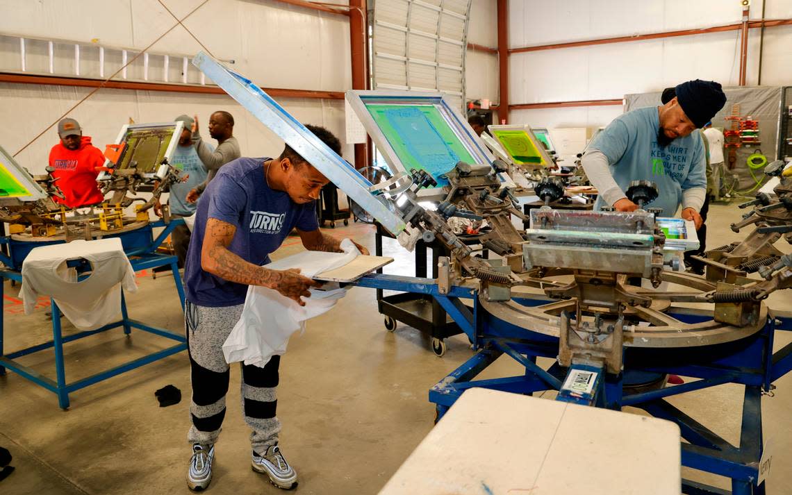 Tyrone Hollins, left, and Joseph Frasier work in the Turn 90 program screen printing shop. Turn 90 helps with the reentry process by helping formerly incarcerated men with life skills.