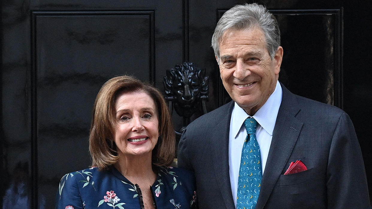 Nancy Pelosi and husband Paul Pelosi pose for the media in front of a door.