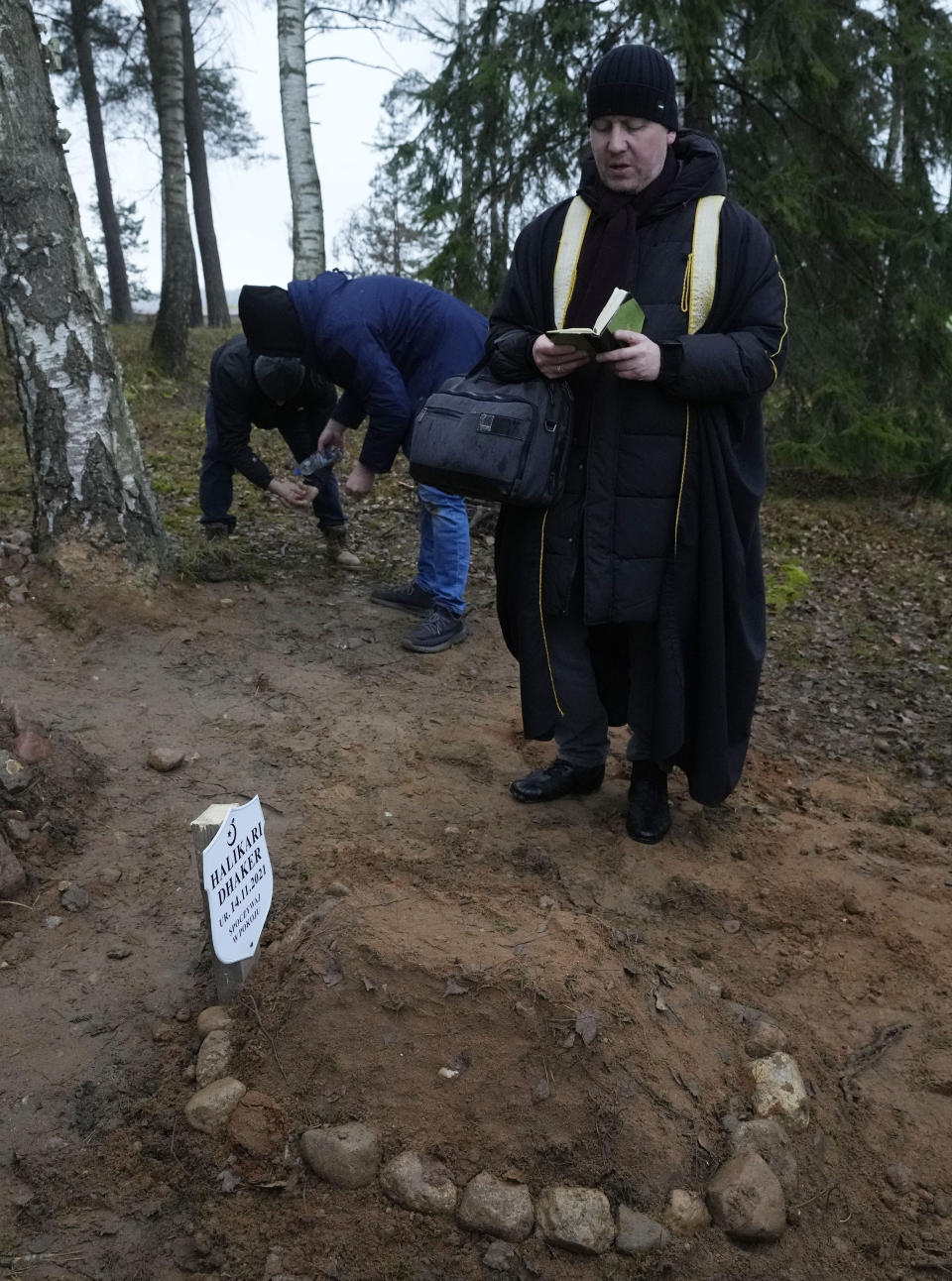 A Polish imam, right, and two other members of a Muslim community bury the tiny white casket of an unborn Iraqi boy, in Bohoniki, Poland, on Tuesday Nov. 23, 2021. The child is the latest life claimed as thousands of migrants from the Middle East have sought to enter the European Union but found their path cut off by a military build-up and fast approaching winter in the forests of Poland and Belarus. (AP Photo/Czarek Sokolowski)