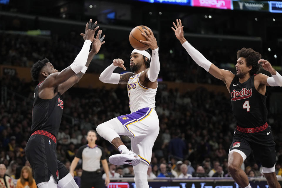 Los Angeles Lakers guard D'Angelo Russell, center, shoots as Portland Trail Blazers center Deandre Ayton, left, and guard Matisse Thybulle defend during the first half of an NBA basketball game Sunday, Nov. 12, 2023, in Los Angeles. (AP Photo/Mark J. Terrill)