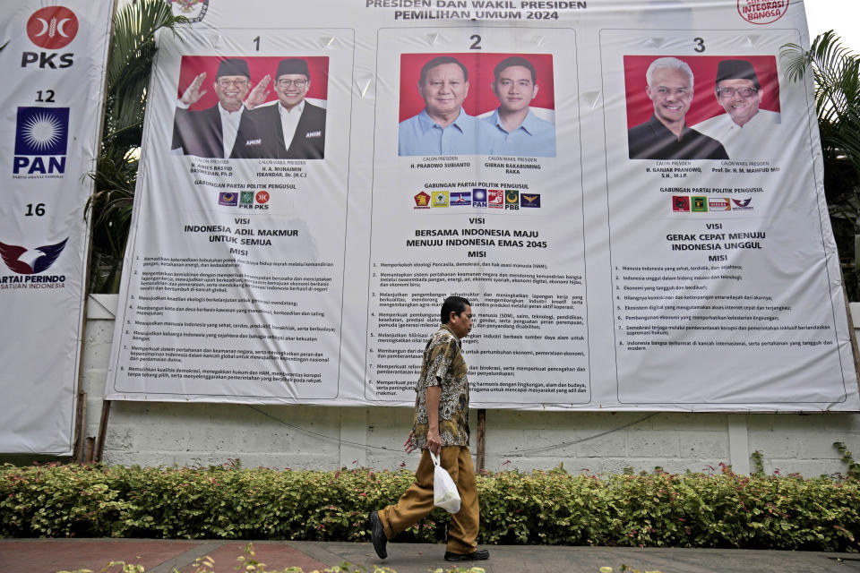 A man walks past an election banner introducing presidential candidates, from left, Anies Baswedan and Muhaimin Iskandar, Prabowo Subianto and his running mate Gibran Rakabuming Raka who is also the eldest son of Indonesian President Joko Widodo, and Ganjar Pranowo and his running mate Mahfud MD, in Jakarta, Indonesia, Thursday, Feb. 1, 2023. Indonesians on Wednesday, Feb. 14, 2024 will elect the successor to popular President Joko Widodo, who is serving his second and final term. It is a three-way race for the presidency among current Defense Minister Prabowo Subianto and two former governors, Anies Baswedan and Ganjar Pranowo. (AP Photo/Dita Alangkara)