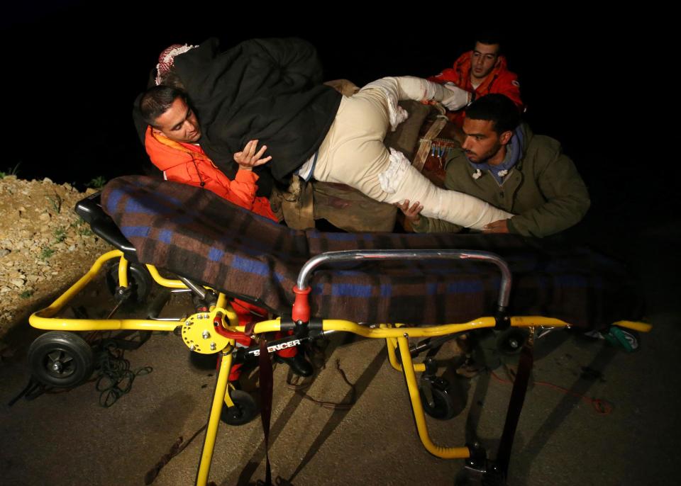 In this picture taken early Sunday, April 20, 2014, a Syrian volunteer, right, and a Lebanese Red Cross volunteer, left, move Saleh Zawaraa, 28, from a horse onto a stretcher after a 12-hour journey from the Syrian village of Beit Jinn, near the Israeli-occupied Golan Heights, over the 2,814-meter (9,232-foot) high Mount Hermon (Jabal el-Sheikh), into the town of Chebaa, in southeast Lebanon. Saleh said he was hit by a tank shell outside of Beit Jinn while trying to bring bread into the village.(AP Photo/Hussein Malla)