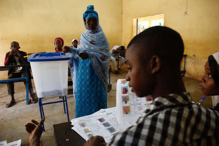 An electoral worker checks voters lists as a woman stands near a ballot box during a run-off presidential election in Bamako, Mali August 12, 2018. REUTERS/Luc Gnago