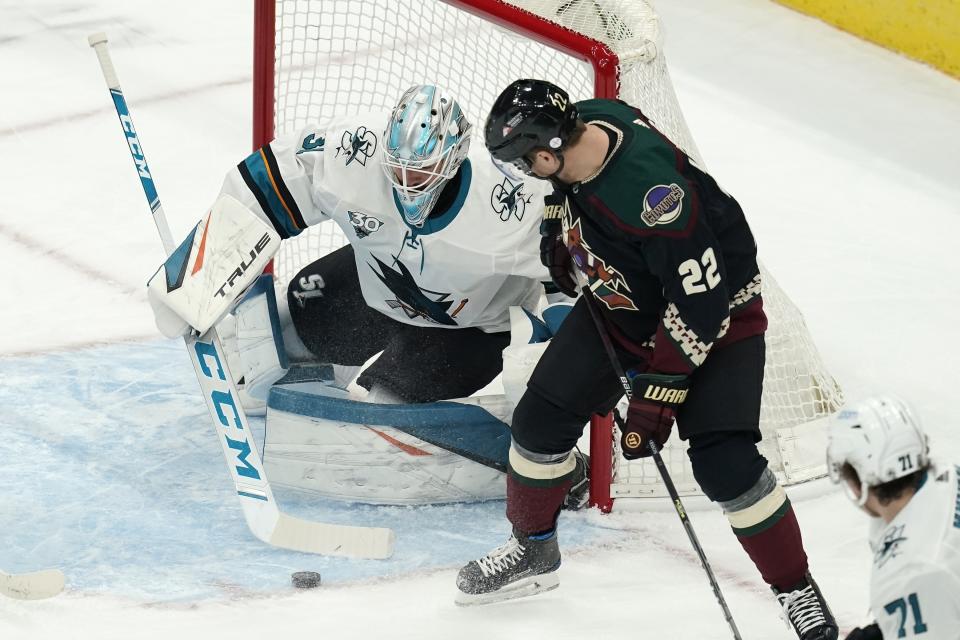 San Jose Sharks goaltender Martin Jones, left, makes a save on a shot as Arizona Coyotes left wing Johan Larsson (22) looks on during the first period of an NHL hockey game Thursday, Jan. 14, 2021, in Glendale, Ariz. (AP Photo/Ross D. Franklin)