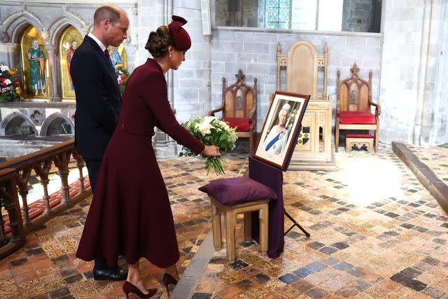 <p>Toby Melville - WPA Pool/Getty Images</p> Prince William and Kate Middleton lay flowers during a service at St Davids Cathedral on the first anniversary of Queen Elizabeth's death on Sept. 8 in St Davids, Wales