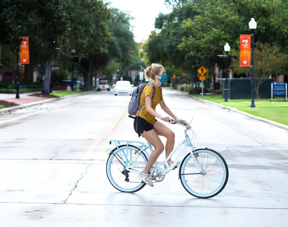 A student rides her bike through the University of Florida campus in 2020.