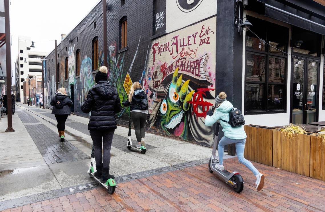 People ride scooters through Freak Alley Gallery in downtown Boise on April 13, 2022. The alleyway, located behind the businesses between 8th Street and 9th Street and Bannock Street and Idaho Street showcases local graffiti style art.