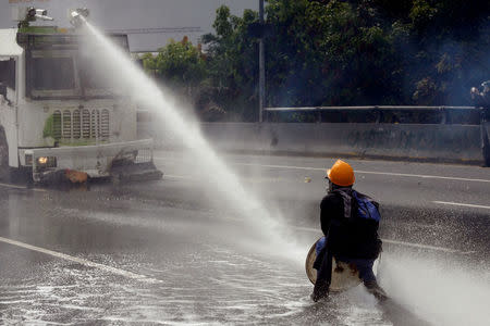 A demonstrator confronts a police water cannon vehicle during a rally called by health care workers and opposition activists against Venezuela's President Nicolas Maduro in Caracas, Venezuela May 22, 2017. REUTERS/Marco Bello