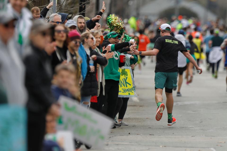 Spectators lining Rockdale Avenue cheer on runners during the 2024 New Bedford Half Marathon.