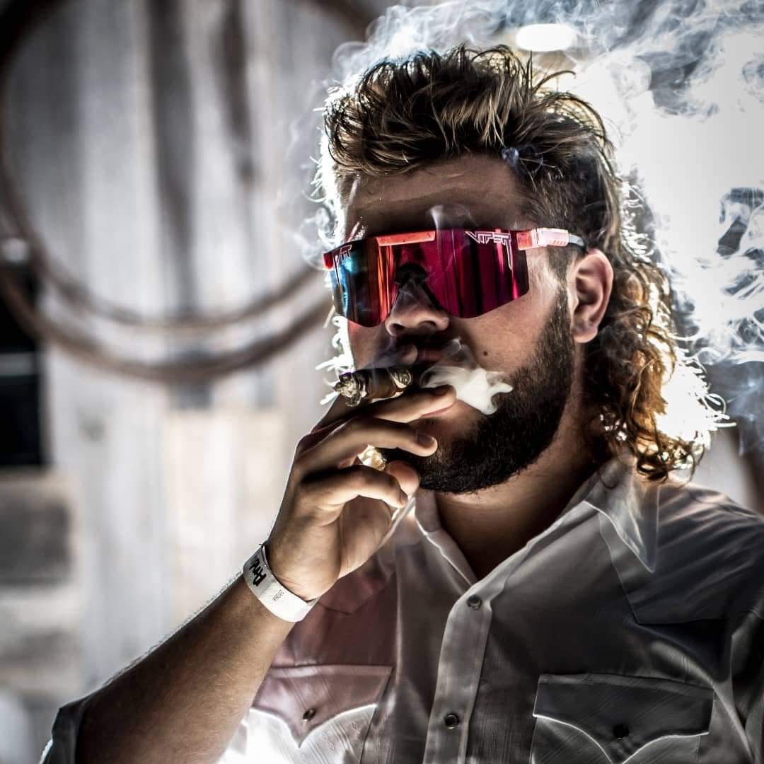 Andy Forster from Menasha, Wis., smokes a cigar while posing with his mullet, nicknamed the "Wisconsin Waterfall," in the 2022 USA Mullet Championships.