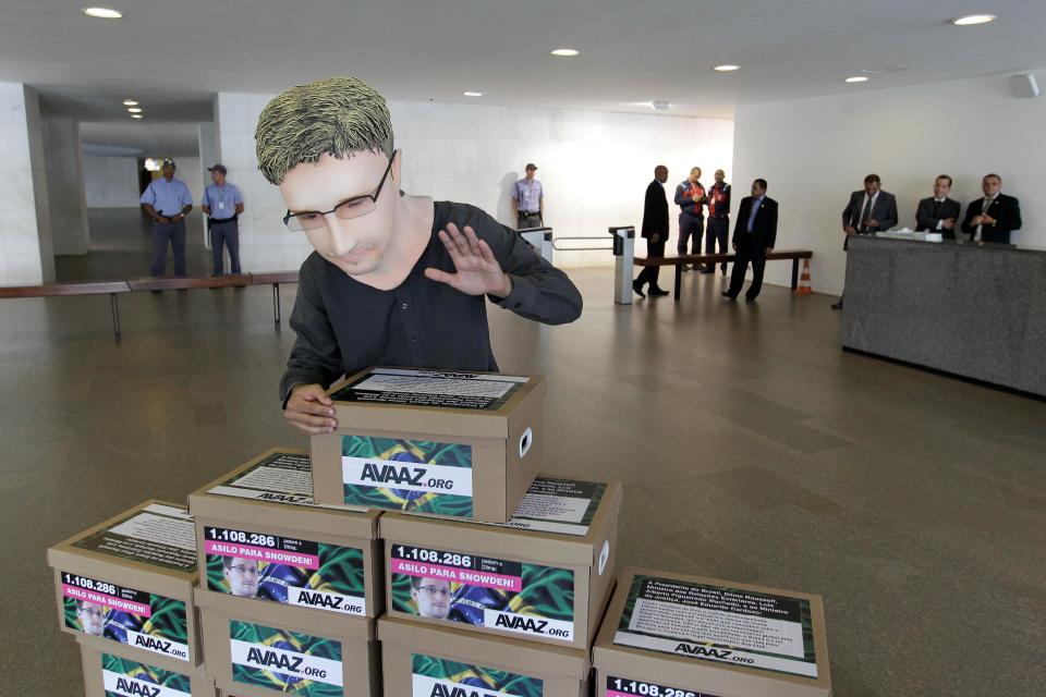 An activist wearing a mask of former NSA analyst Edward Snowden poses with boxes of signatures asking for Brazil's government to give him asylum, in the lobby of the foreign ministry in Brasilia, Brazil, Thursday, Feb. 13, 2014. Last year, Snowden revealed that the United States collected data on billions of telephone and email conversations in Latin America's biggest country, including Brazilian President Dilma Rousseff's communications with aides. (AP Photo/Eraldo Peres)