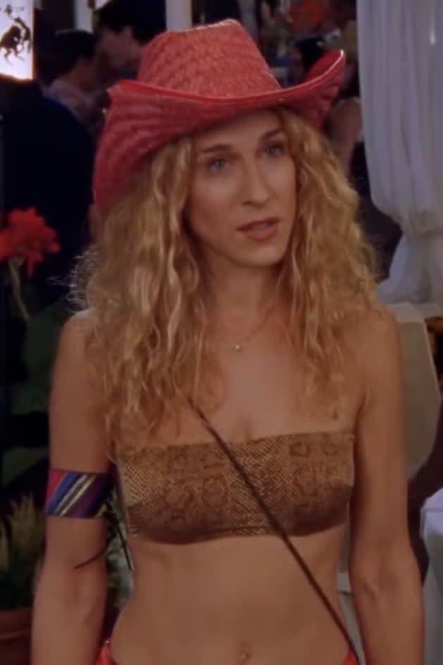 Sarah Jessica Parker in a midriff-baring outfit with a straw hat at a crowded outdoor event in 