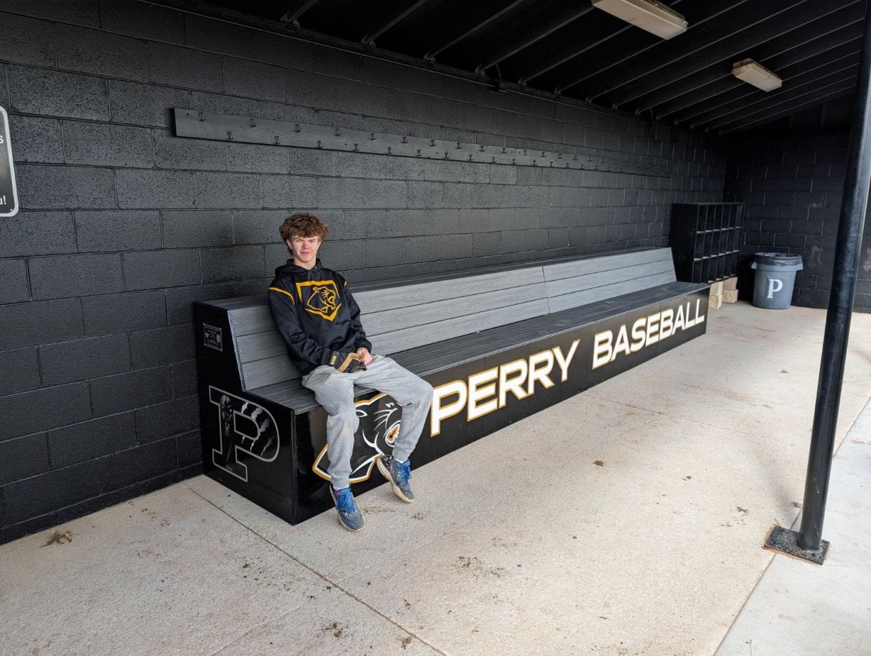 Perry High School baseball player Bryan Witmer sits on the bench he helped build at the school's baseball field as part of his Eagle Scout project.