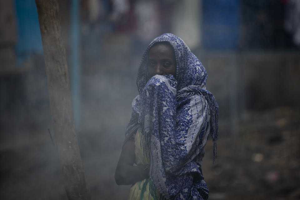 A displaced Tigrayan woman covers her face from the smoke of a wood fire as she prepares "Injera" flatbread at the Hadnet General Secondary School which has become a makeshift home to thousands displaced by the conflict, in Mekele, in the Tigray region of northern Ethiopia Wednesday, May 5, 2021. The Tigray conflict has displaced more than 1 million people, the International Organization for Migration reported in April, and the numbers continue to rise. (AP Photo/Ben Curtis)