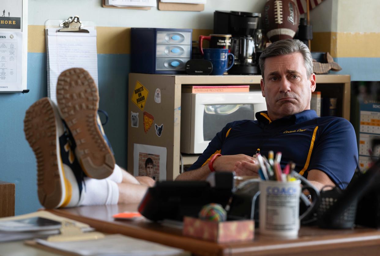 Jon Hamm sits with his feet up on his classroom desk in a scene from Mean Girls