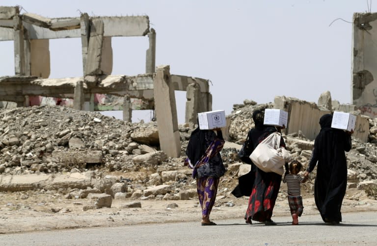 Iraqi women walk past destroyed buildings south of Mosul on May 26, 2017