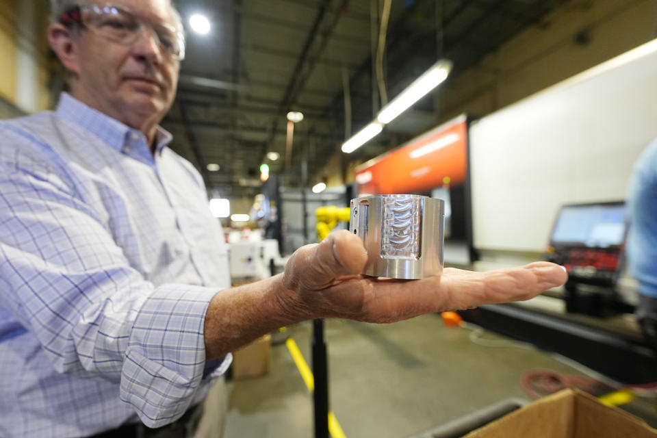 Grady Cope, CEO of Reata Engineering & Machine Works, holds up a solenoid housing for a blood plasma pump, Thursday, Feb. 15, 2024, in Englewood, Colo. At Reata, which makes parts for aircraft and medical device manufacturers, "efficiency was kind of forced on us,'' Cope said. (AP Photo/David Zalubowski)