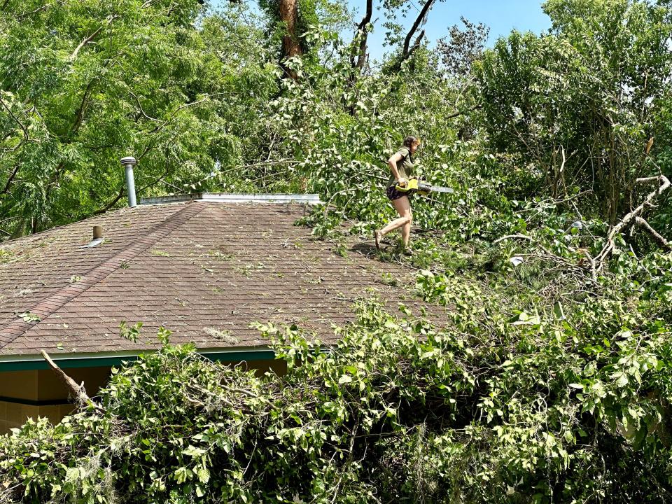 Laura Floyd takes a chainsaw to trees that fell on her roof on West Indianhead Drive after tornadoes in the area on Friday, May 10, 2024.