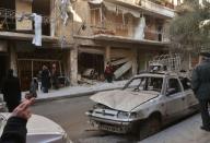 Syrian residents look at the damage following reported rebel shelling in Aleppo's government-controlled neighbourhood of Suleimaniyeh, on February 14, 2016