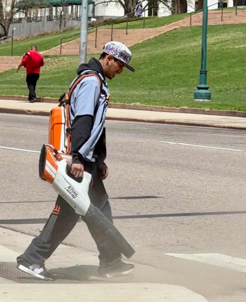 A worker uses a battery-powered leaf blower to  clean gutters in Denver, Colorado. Some regulators are considering limiting the sale and use of gas-powered lawn equipment in the Denver area to improve air quality.