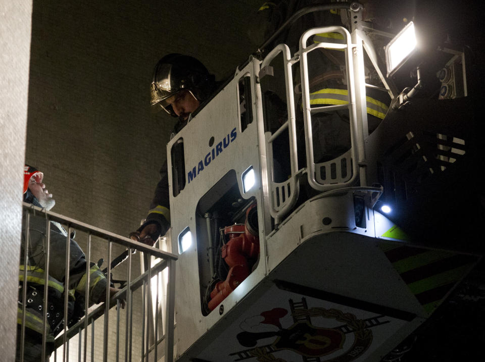 Firefighters work on a snorkel platform over an apartment where six Brazilians died of apparent carbon monoxide poisoning in Santiago, Chile, Wednesday, May 22, 2019. Police commander Rodrigo Soto said officers found four adults and two children dead at the six-story building. The fire department said a high concentration of carbon monoxide was measured in the apartment, which it said was completely closed. (AP Photo/Esteban Felix)