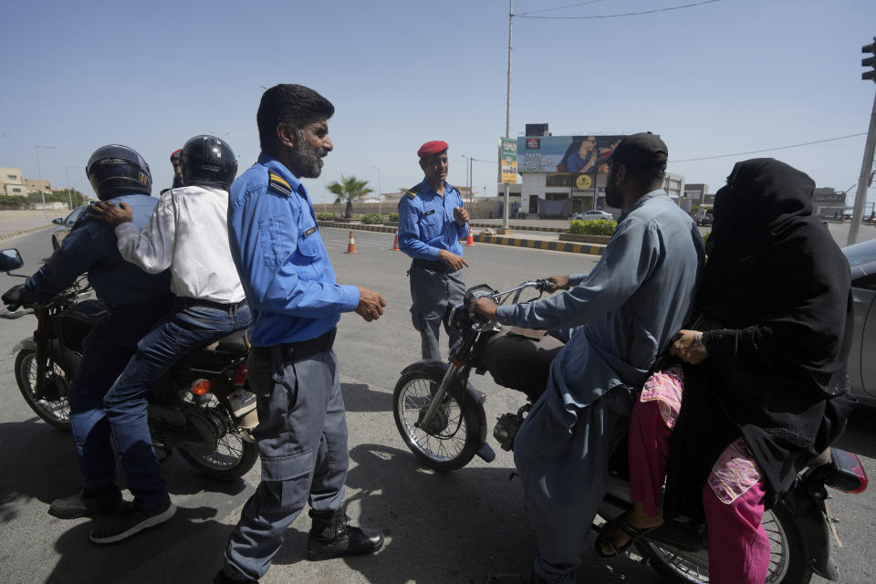 Security personnel brief commuters for alternate route at a barricaded road leading to Clifton beach which closed due to approaching cyclone, in Karachi, Pakistan, Monday, June 12, 2023. India and Pakistan braced for the first severe cyclone this year expected to hit their coastal regions later this week, as authorities on Monday halted fishing activities and deployed rescue personnel. (AP Photo/Fareed Khan)