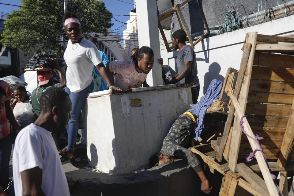 FILE - People look at a body after an overnight shooting in the Petion Ville neighborhood of Port-au-Prince, Haiti, March 18, 2024. (AP Photo/Odelyn Joseph, File)